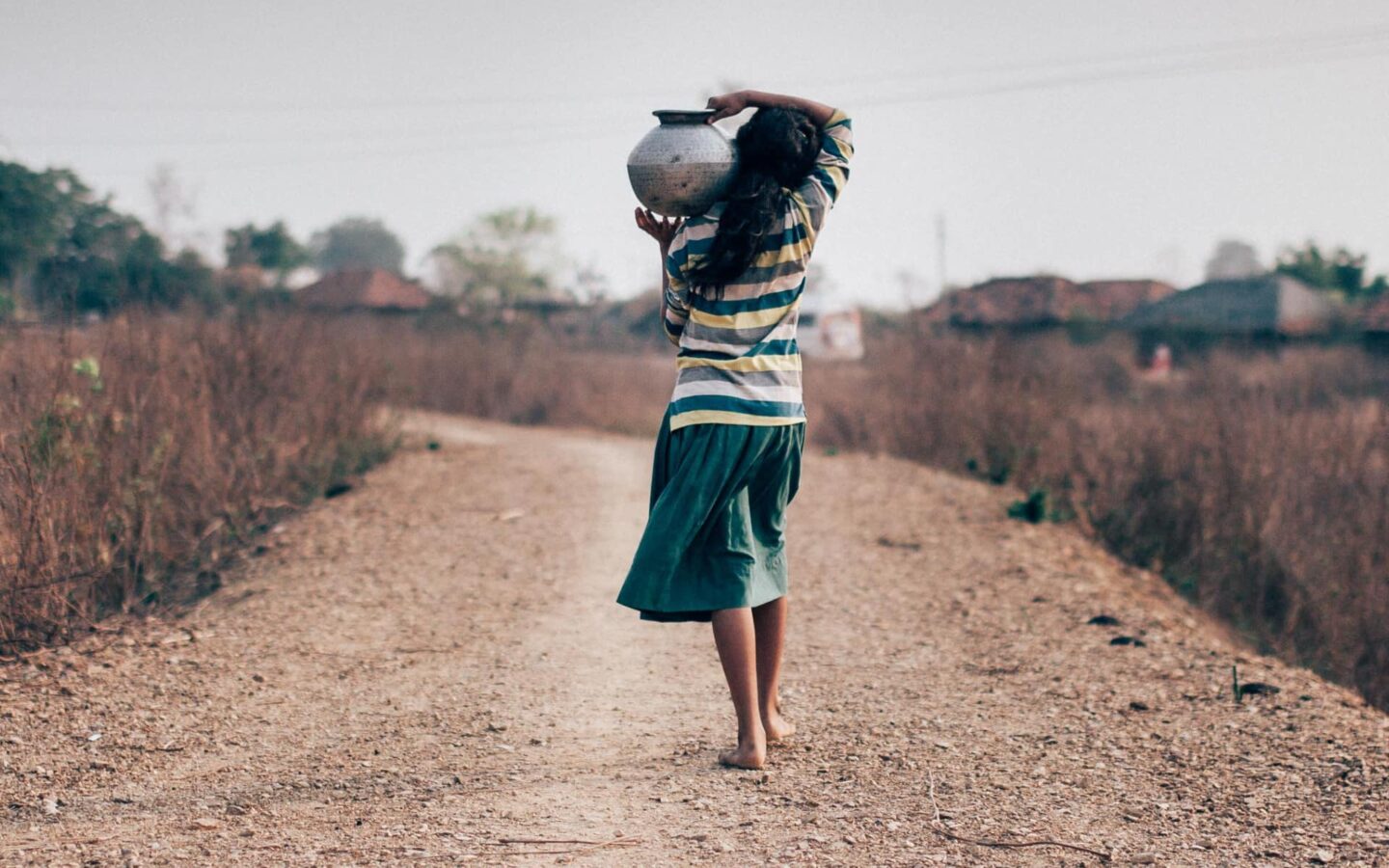 Photograph of a young Indian girl carrying water in a pot on her shoulder
